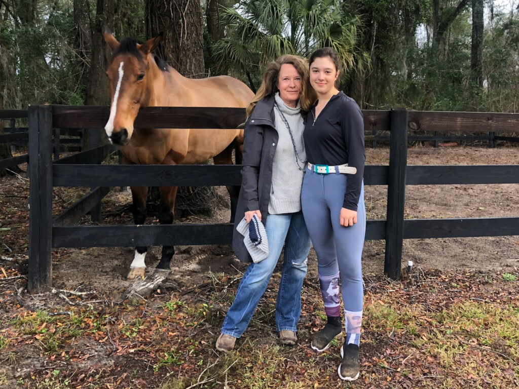 Two women standing next to a horse